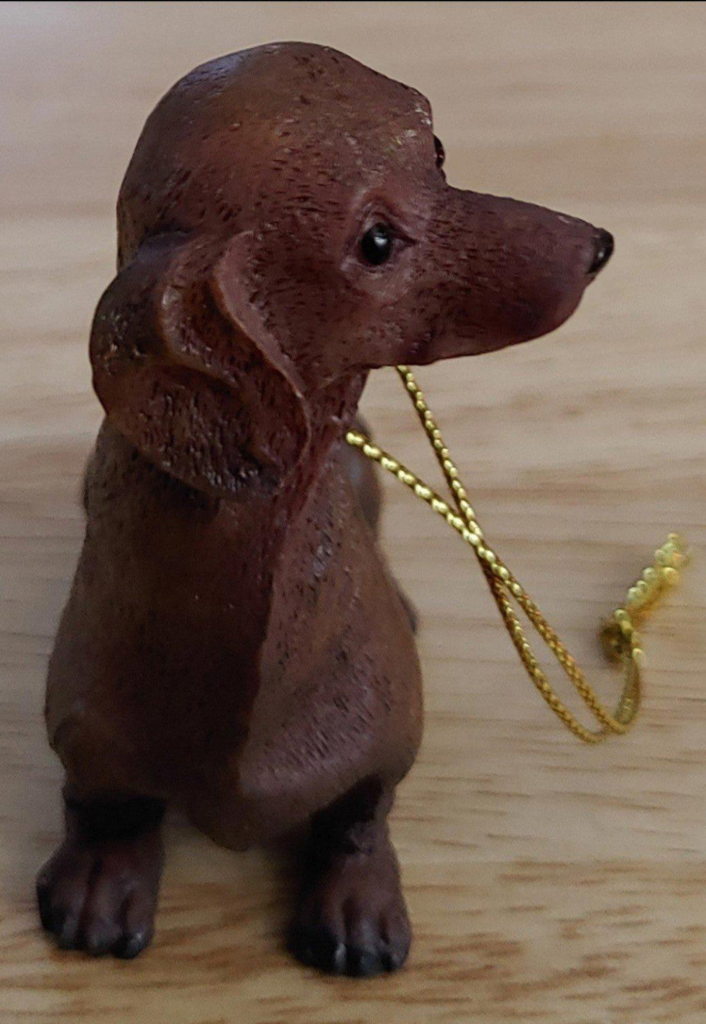 Chocolate brown dachshund ornament figurine from side view with gold cord