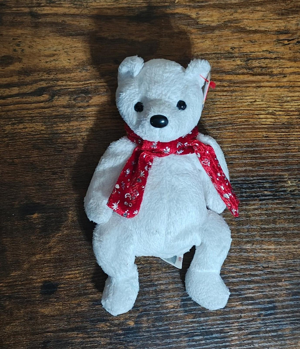 White bear plush upright on wooden surface with red holiday scarf