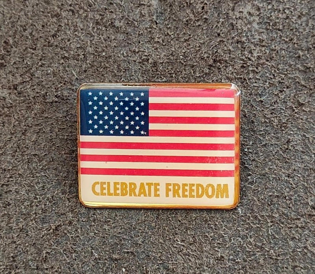 Front view of gold-tone patriotic flag pin with “CELEBRATE FREEDOM”