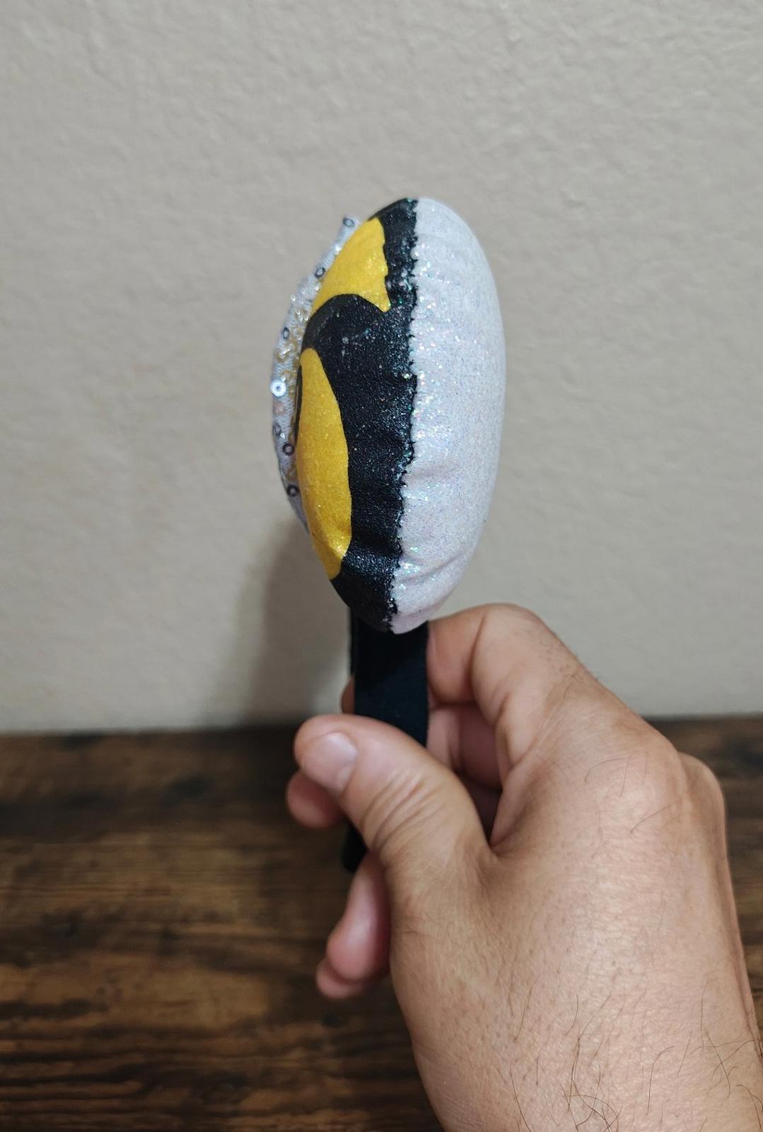 Black headband with glittery white sequin ear with yellow swirl and black oval