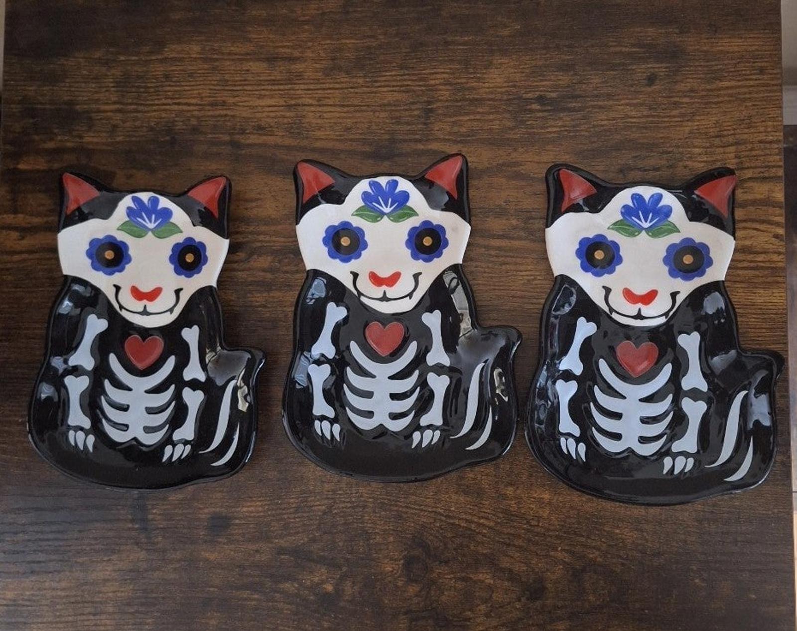 Three black 3D cat sugar skull trinket plates arranged in a row with blue face accents