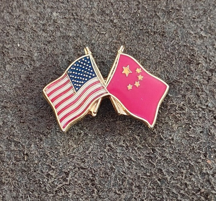 Enamel pin featuring crossed US flag and pink China flag with star details in gold.
