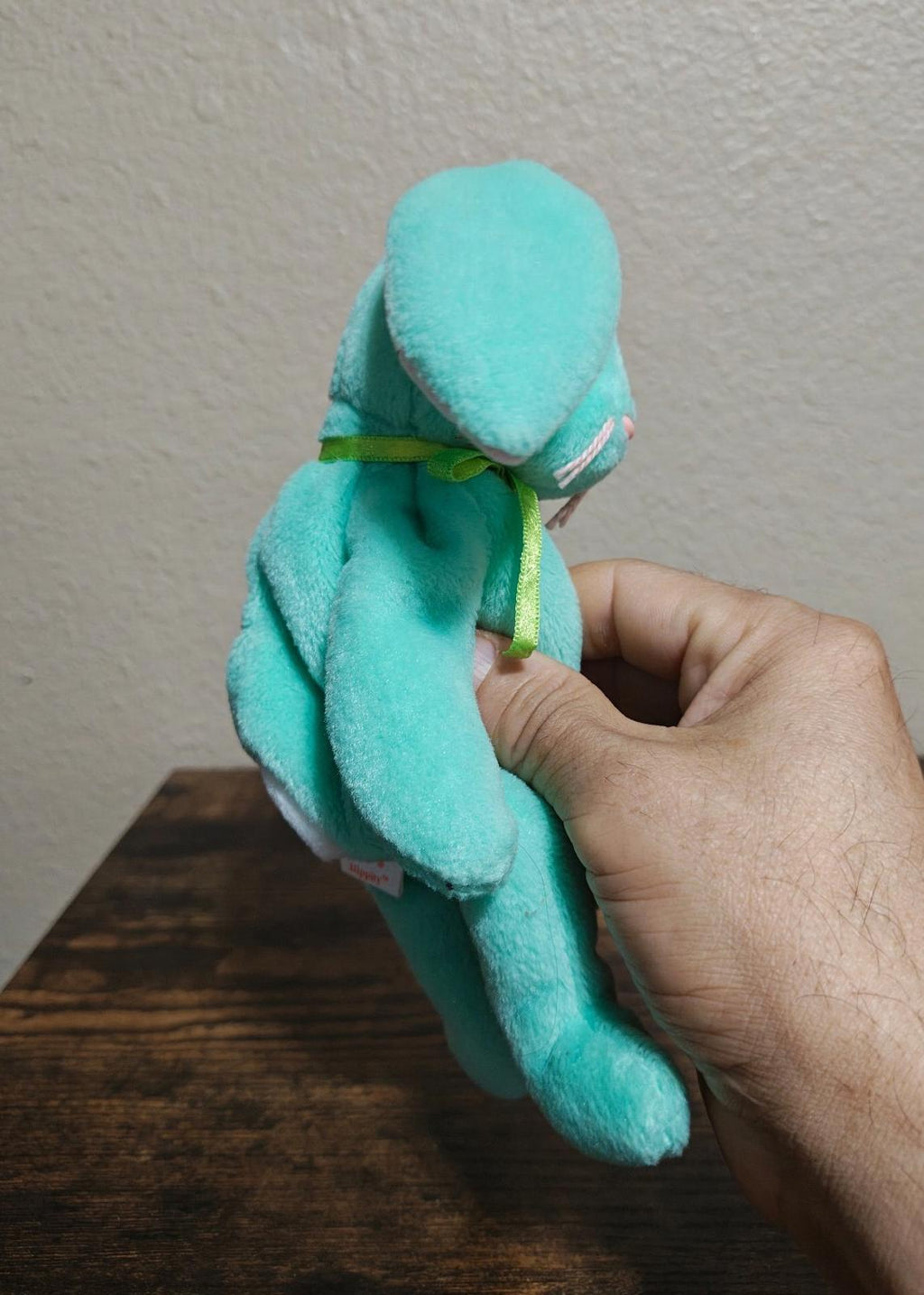 Teal plush bunny beanbag side view with long ears and green ribbon around neck