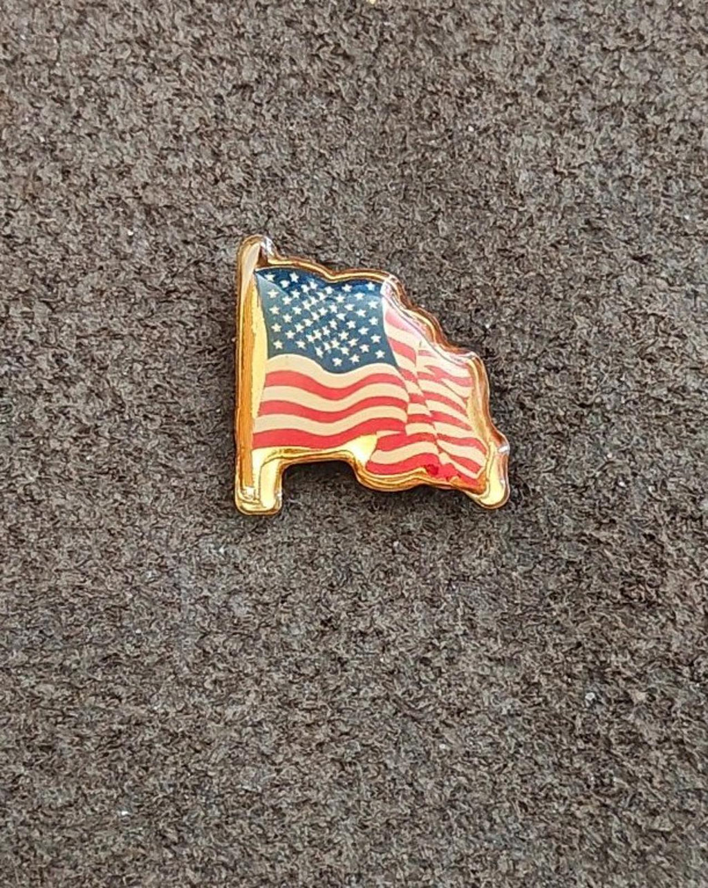 Gold-tone United States flag pin, angled front view with enamel stars and stripes