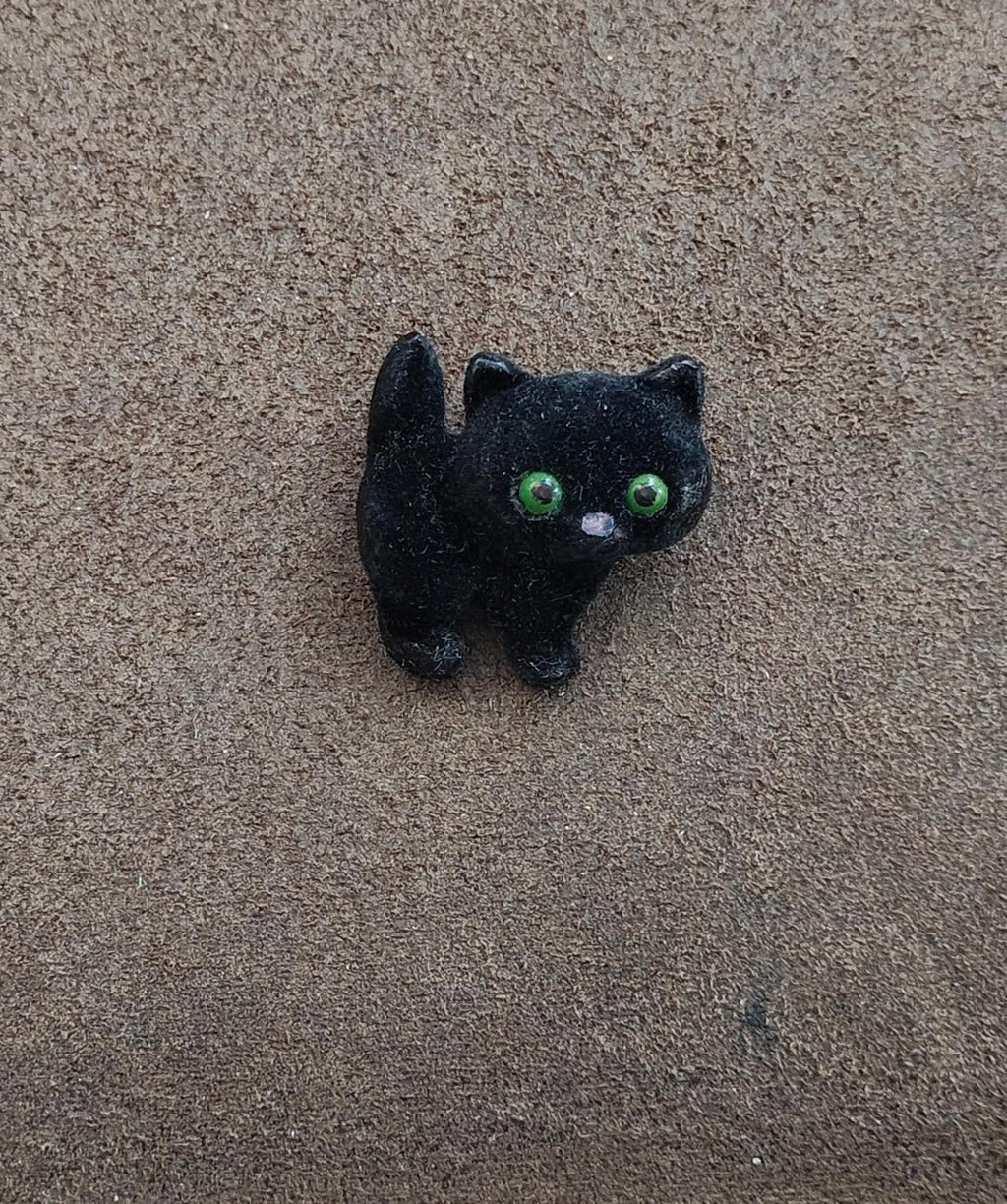 Black fuzzy cat brooch with green eyes, full body view