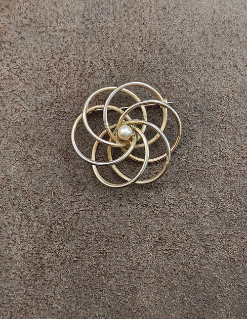 Gold tone concentric circle brooch with pearl center, layered metal rings