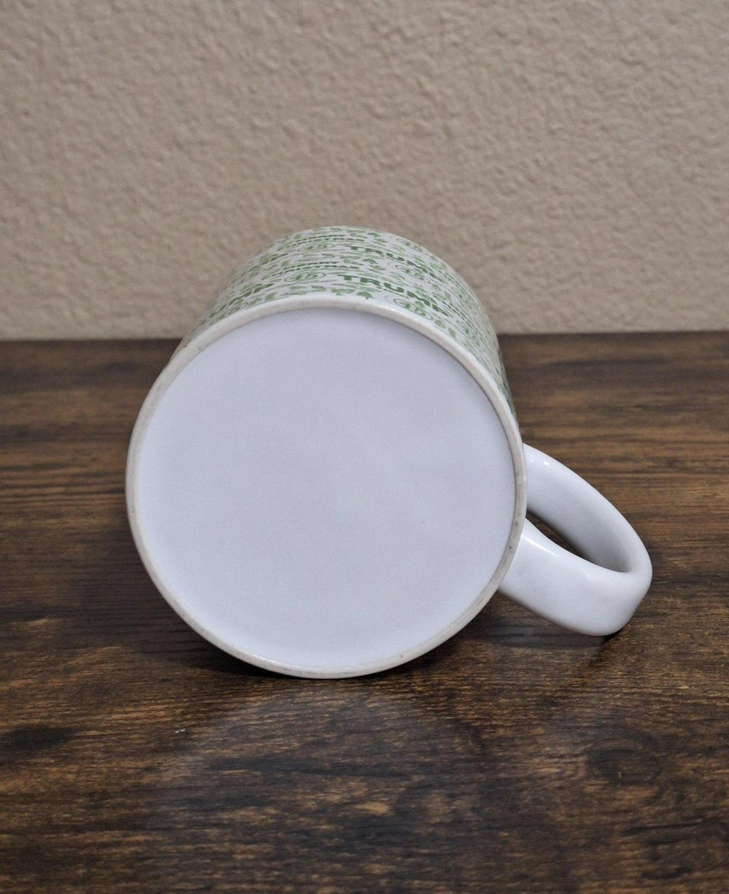 Ceramic mug underside and interior rim view, white mug with green patterned exterior edge.