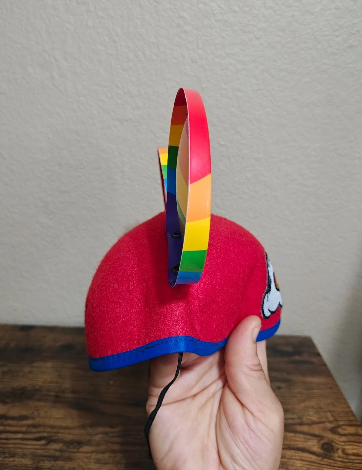 Side view of red felt Mickey Mouse ear hat with rainbow-striped ear and black cord