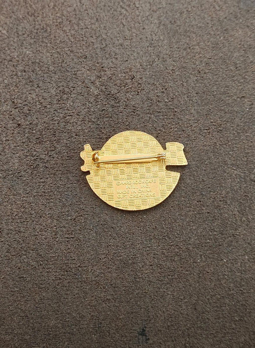 Gold-tone enamel pin back with ridged texture and metal clasp hardware