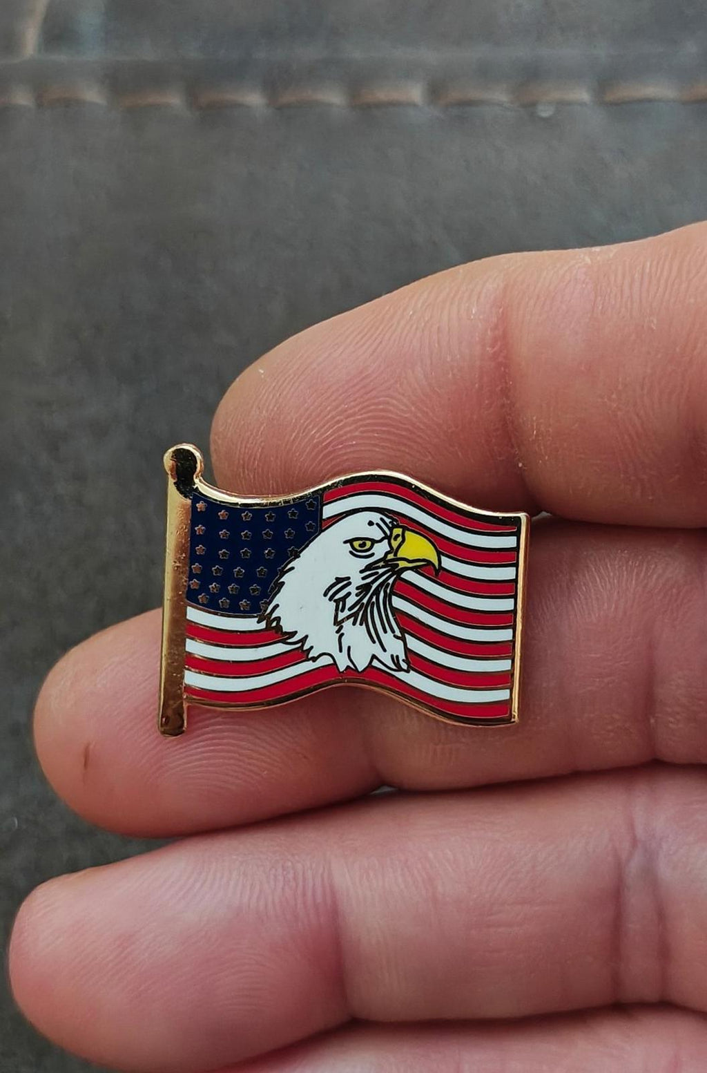 Gold-tone enamel wavy American flag lapel pin with bald eagle, close-up