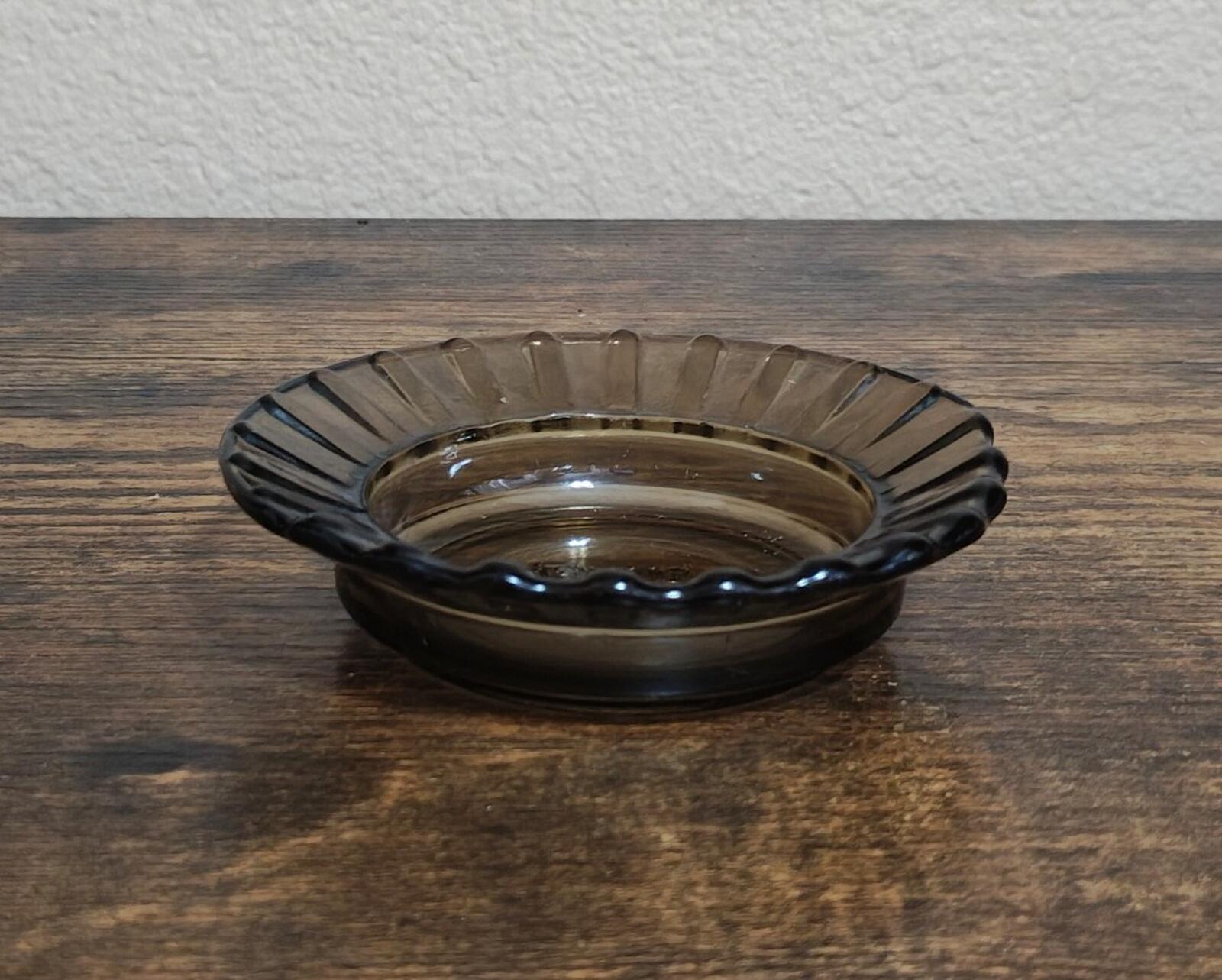 Clear ribbed glass ashtray with dark tint, shallow bowl shape