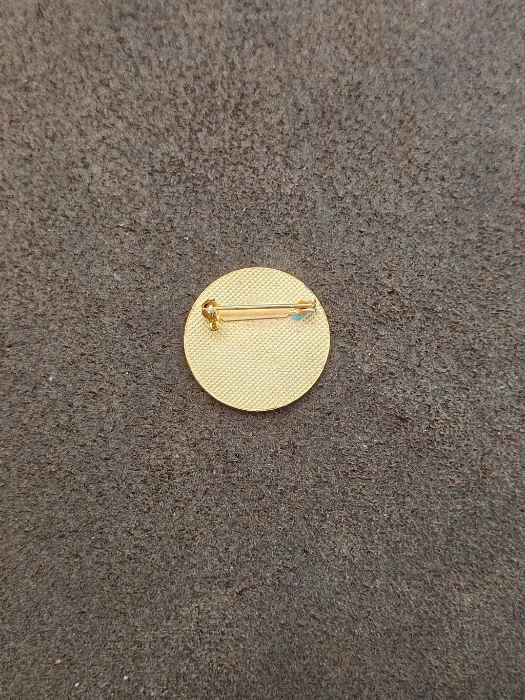 Gold-toned round pin back with safety clasp and pin stem