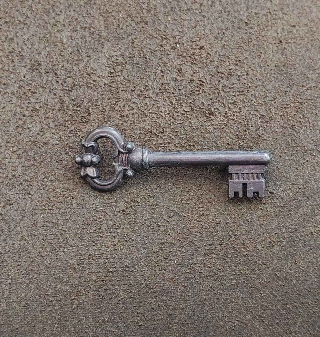 Pewter skeleton key brooch lying flat, round bow and ornate teeth detail