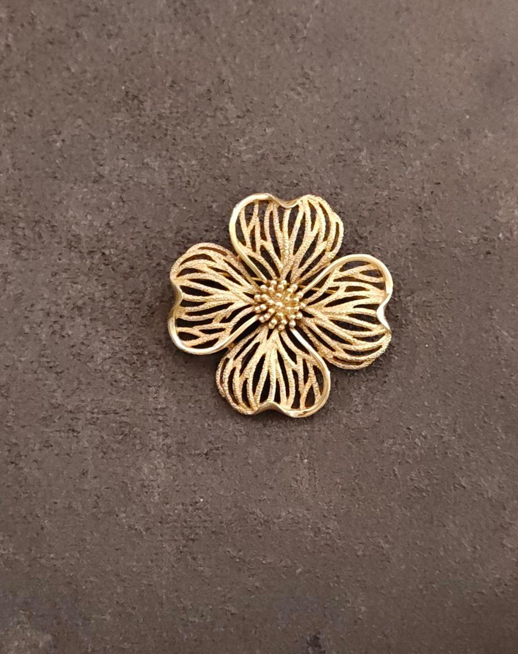 Gold-tone dogwood flower brooch with textured petals and beaded center