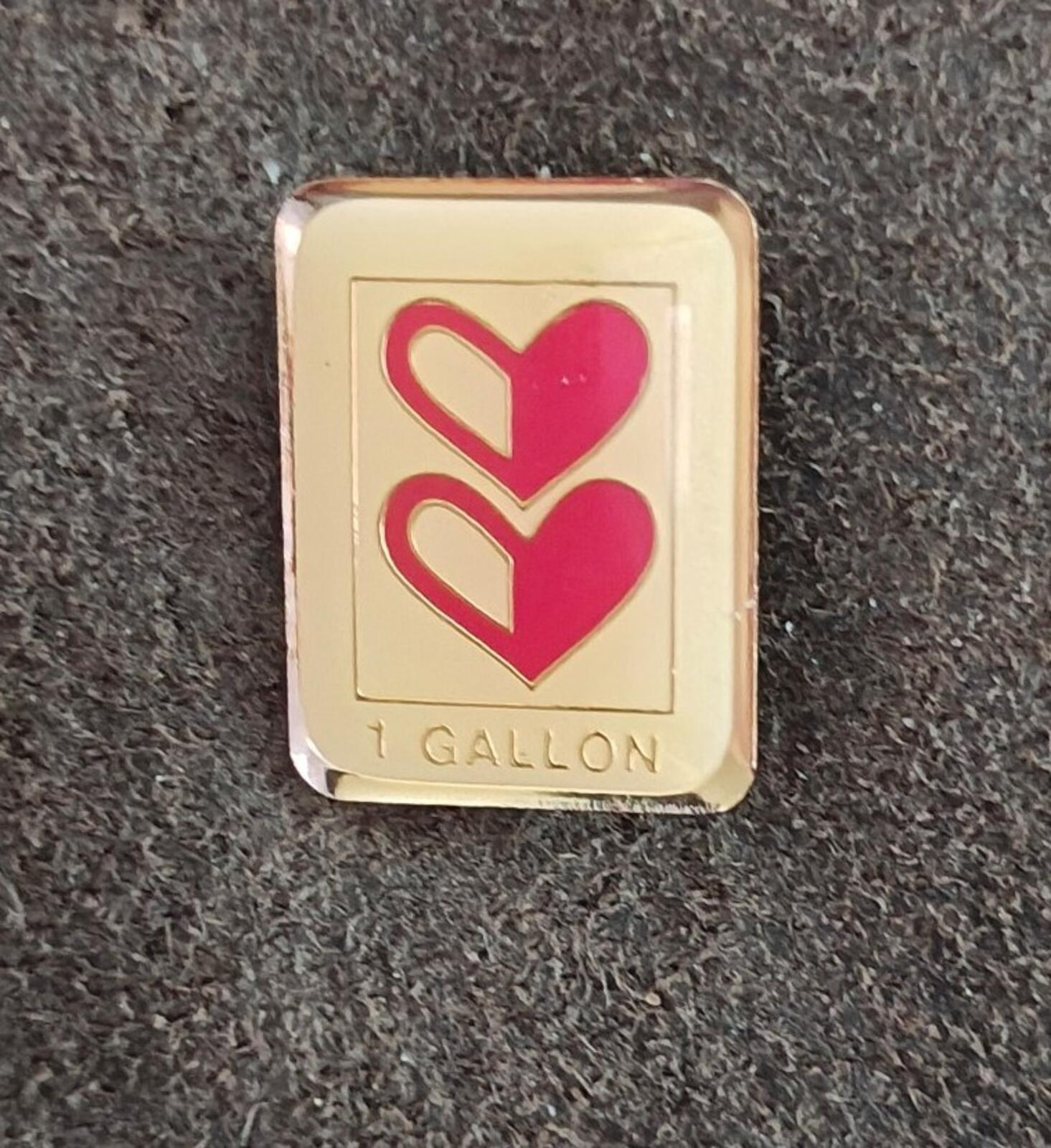 Gold-tone enamel milestone pin with two red hearts and '1 GALLON' at bottom