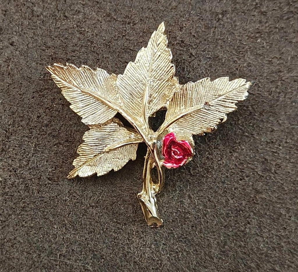 Gold-tone leaf cross pin brooch with red rose and Mary medallion, angled view