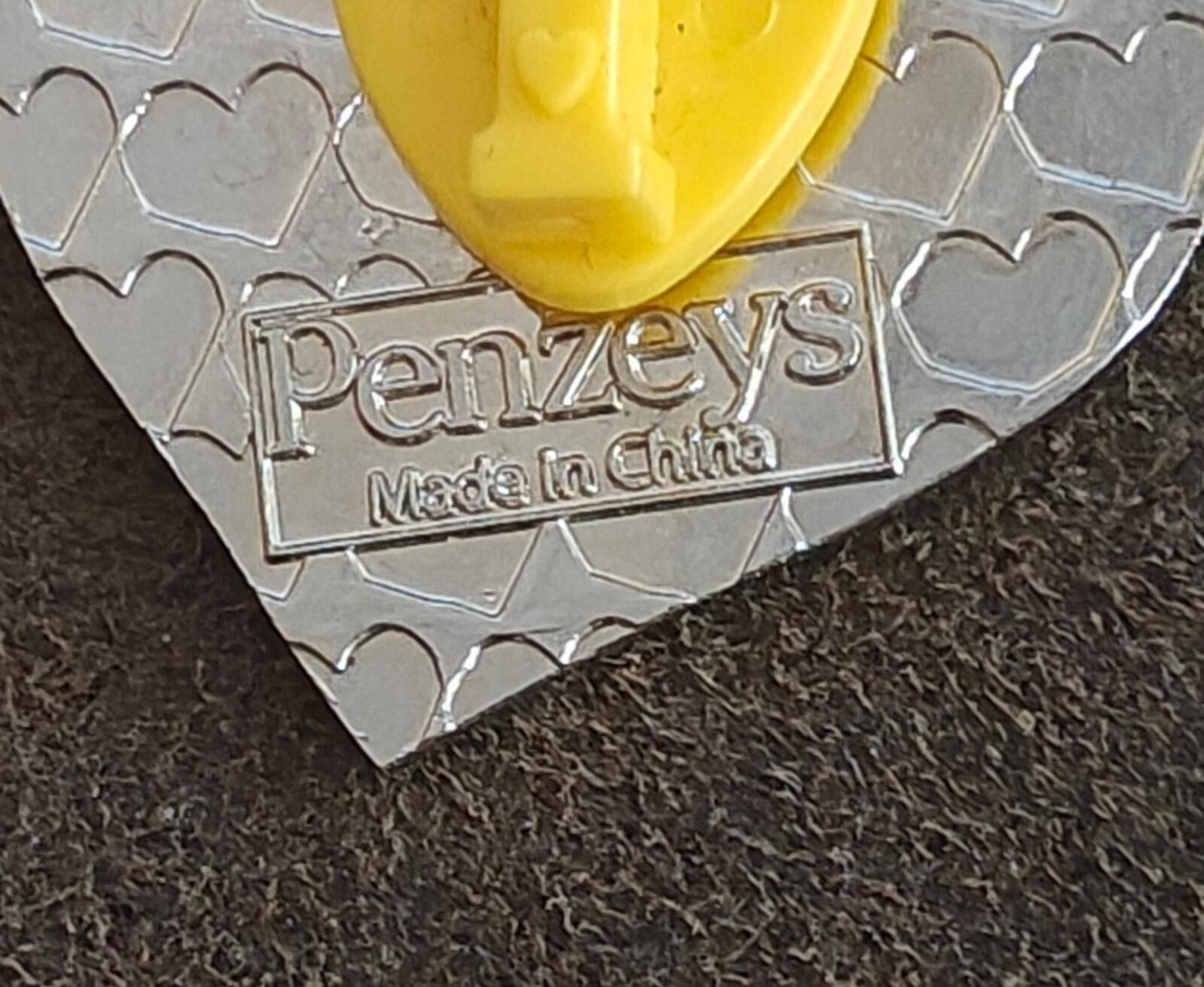Back of Penzeys heart pin with “Penzeys” and “Made in China” stamped on silver backing.