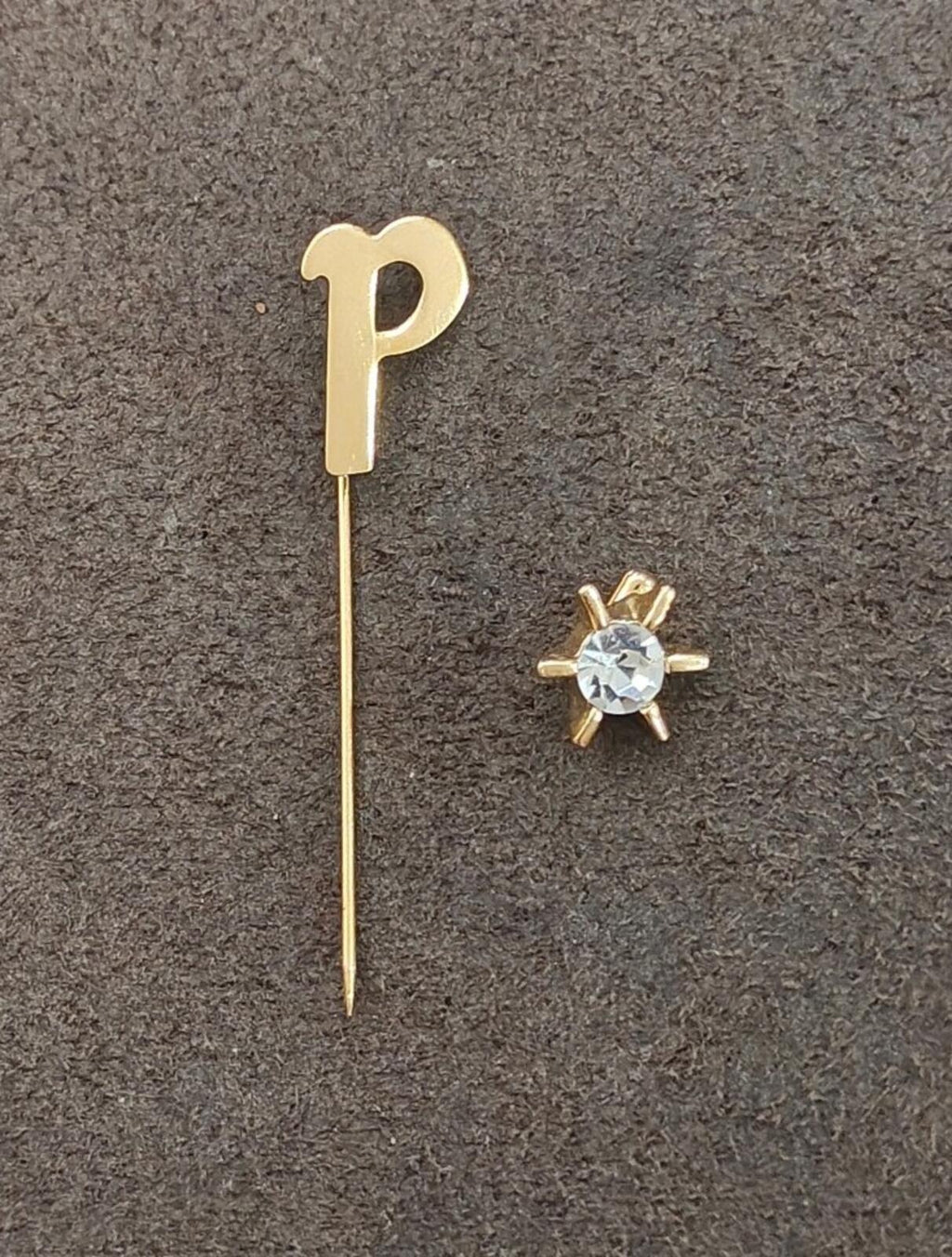 Gold tone initial P stick pin with light-blue round crystal and small gold prongs.