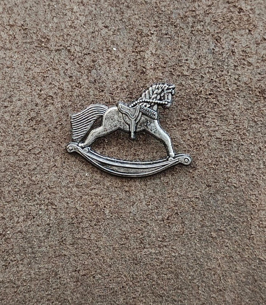 Silver-toned pewter rocking horse pin lying flat, full figure with rocking base.