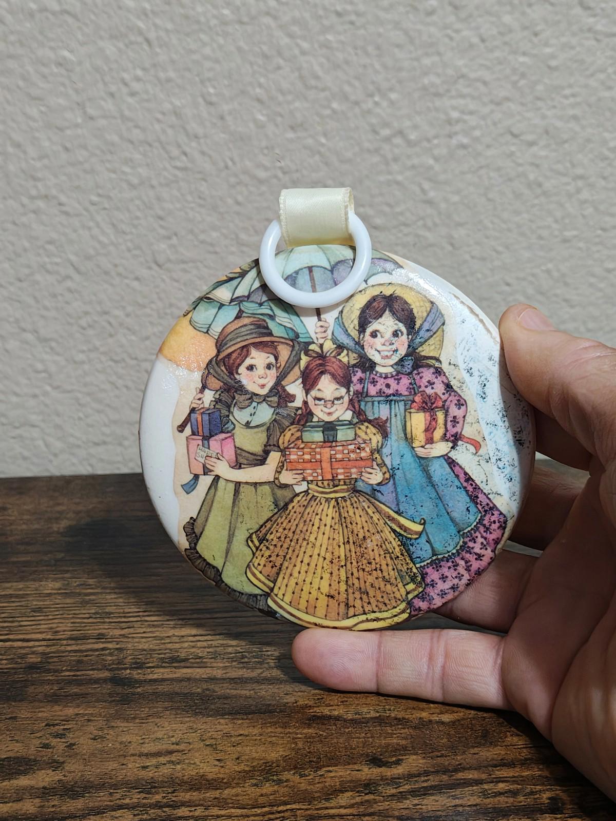 Round hanging ornament with illustrated girls in dresses, cream ribbon top loop
