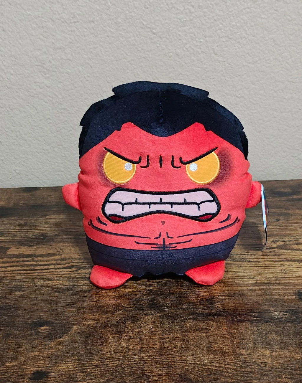 Front view red and navy angry-faced soft plush toy with embroidered expression