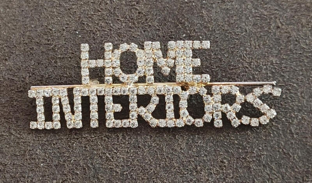 Rhinestone gold-tone brooch spelling "HOME" and "INTERIORS"