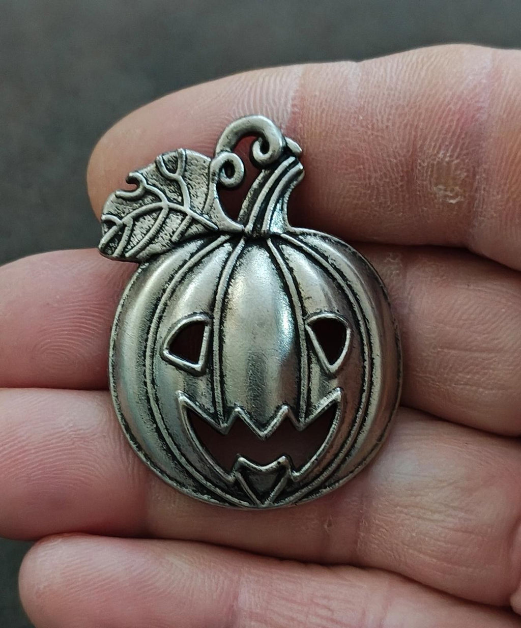 Silver-tone jack-o'-lantern charm pendant, carved pumpkin face with loop bail