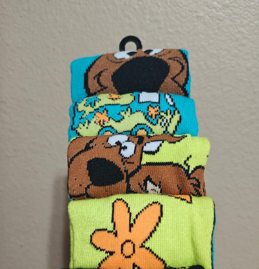 Six pairs of colorful men's crew socks with character artwork, stacked on hanger.