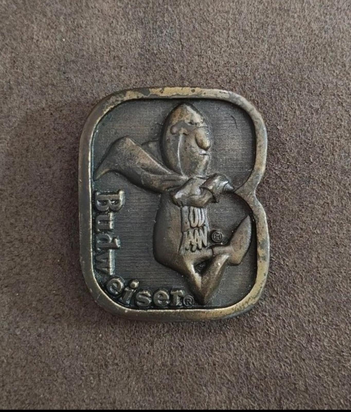 Vintage brass belt buckle front with character in a shield and Budweiser-themed details.