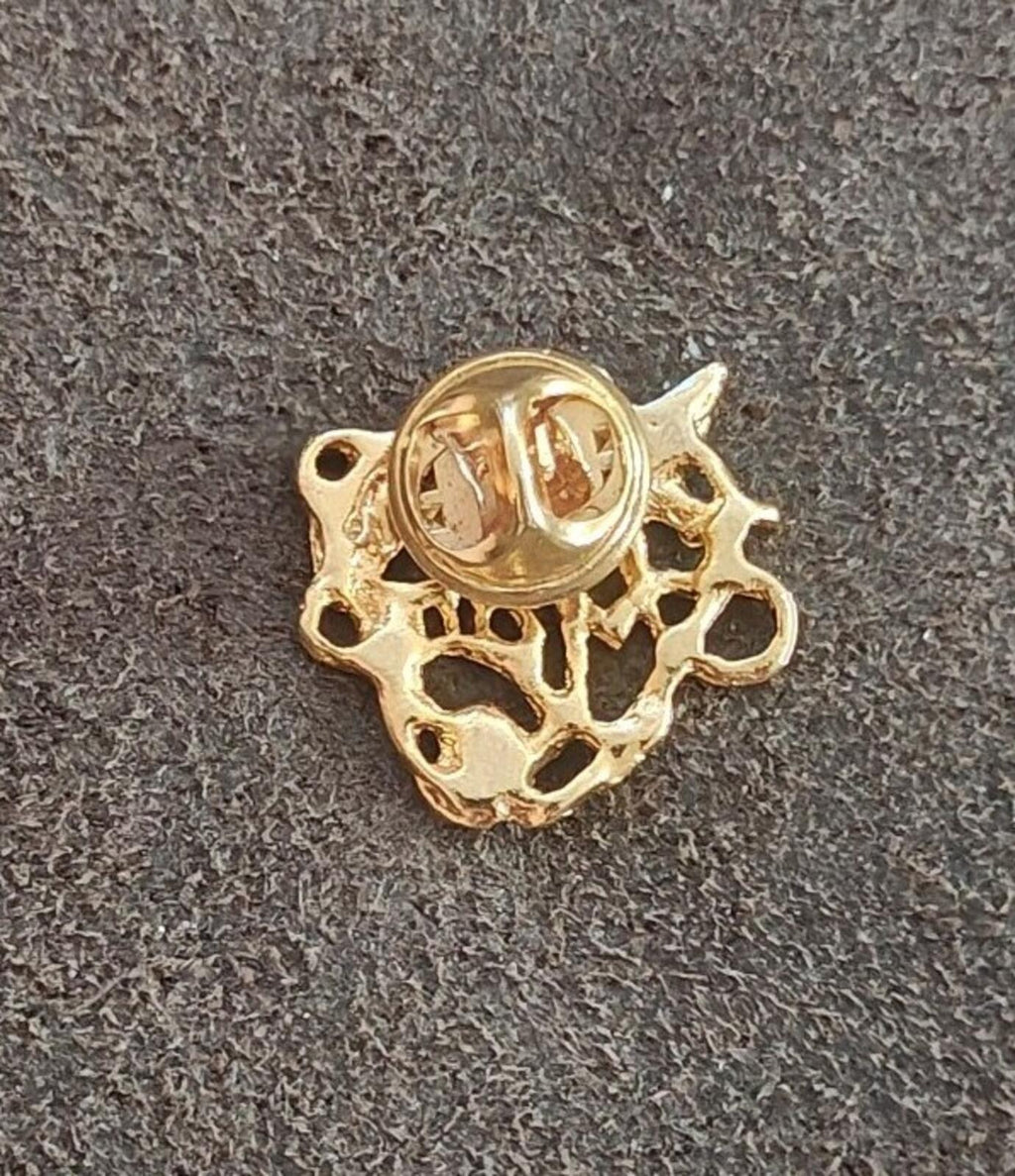 Gold-tone heart pin back view with stamped circular center and loop clasp