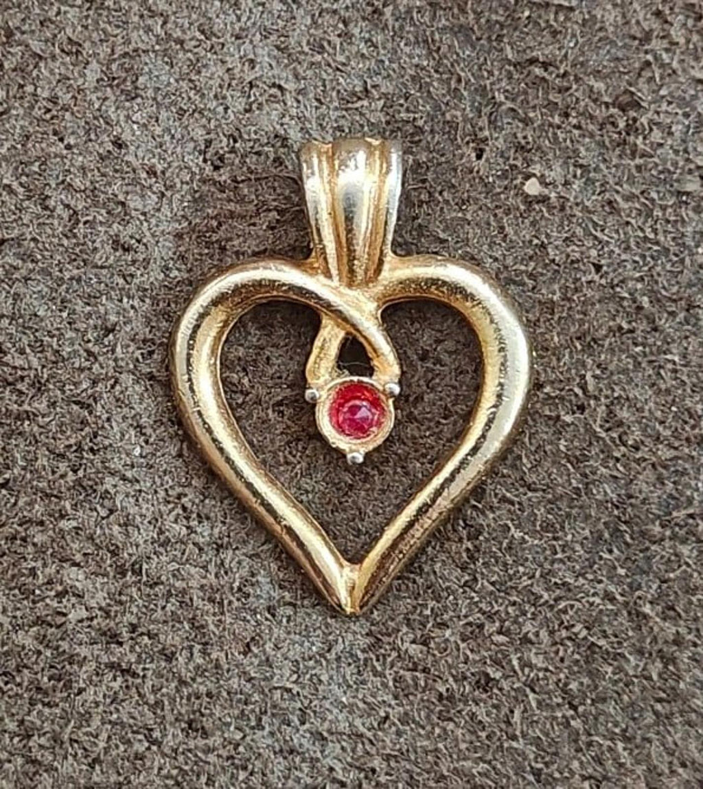 Gold-tone open heart pin with red gemstone set in heart frame