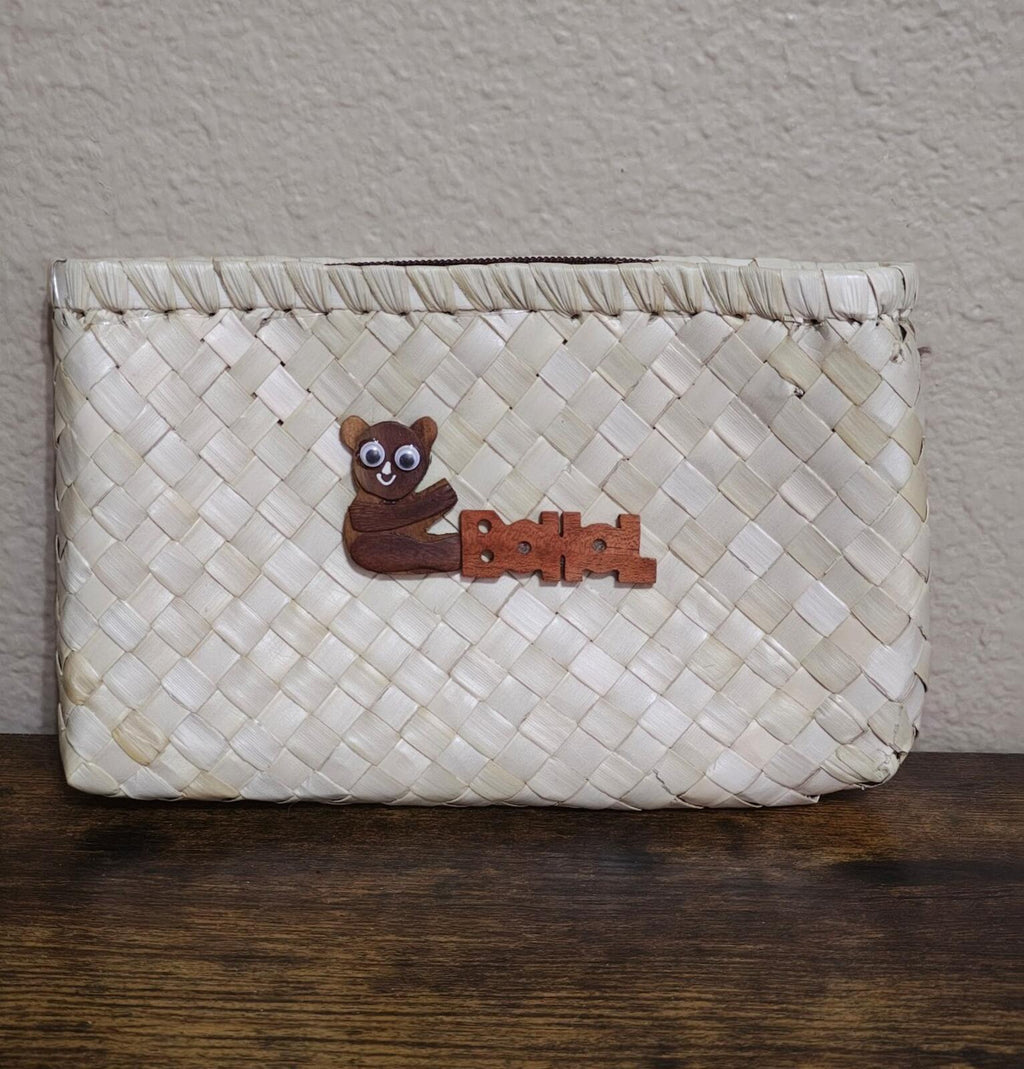 White handwoven pouch with wooden tarsier emblem centered on front