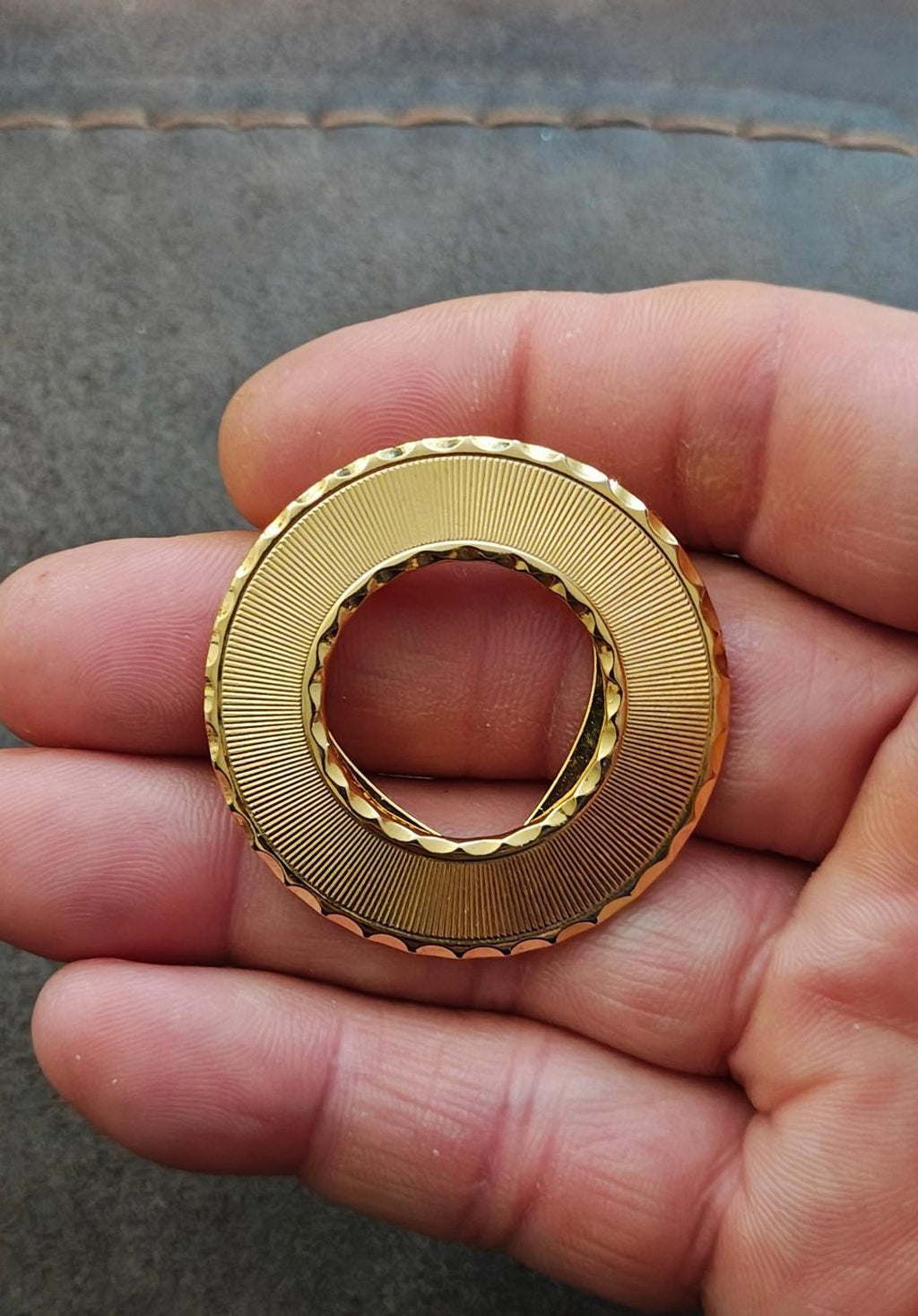 Gold-tone round scarf clip with textured edge and open clasp view