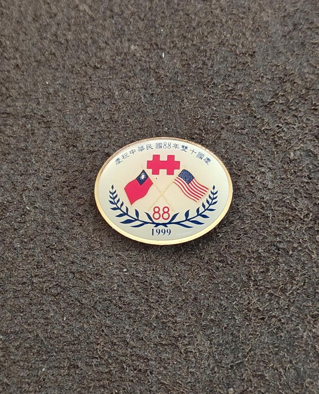 Round gold enamel pin with flags, 88 and 1999, laurel wreath