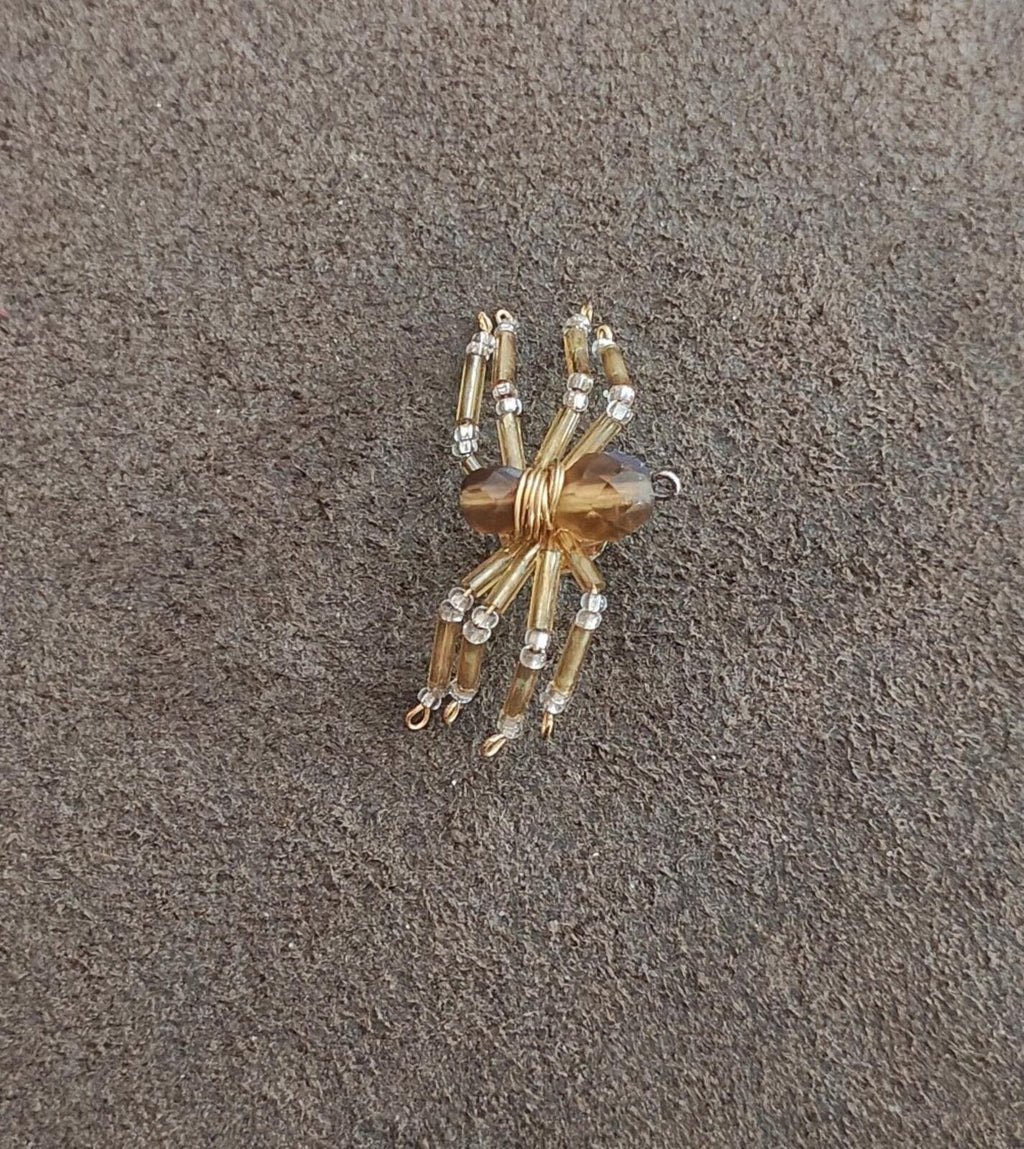 Gold-toned beaded spider pin with clear crystal beads and faceted amber body.