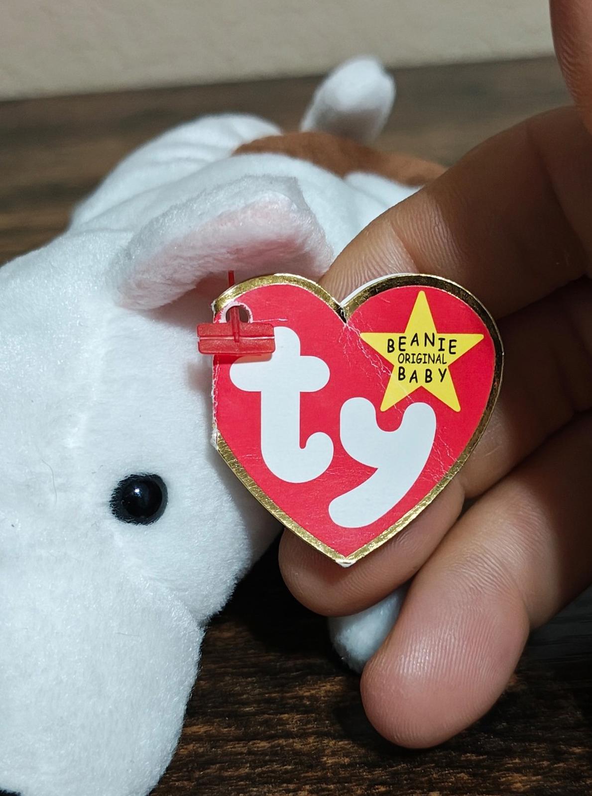 White plush dog close-up with red Ty heart tag shown by fingers