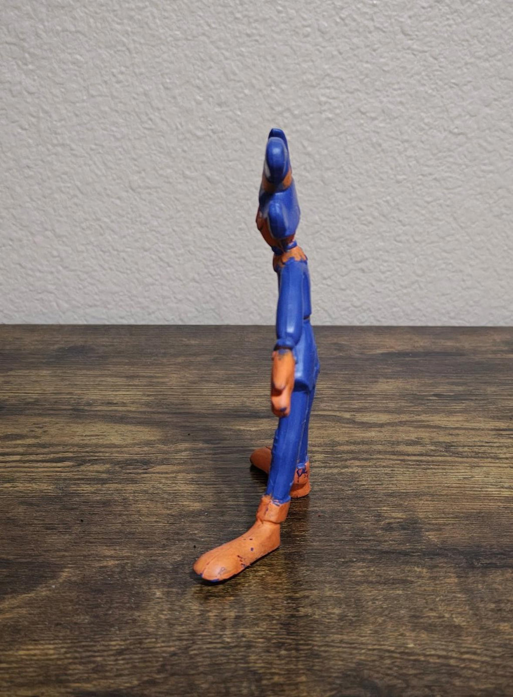 Blue bendy rubber scarecrow figure side profile with orange boots