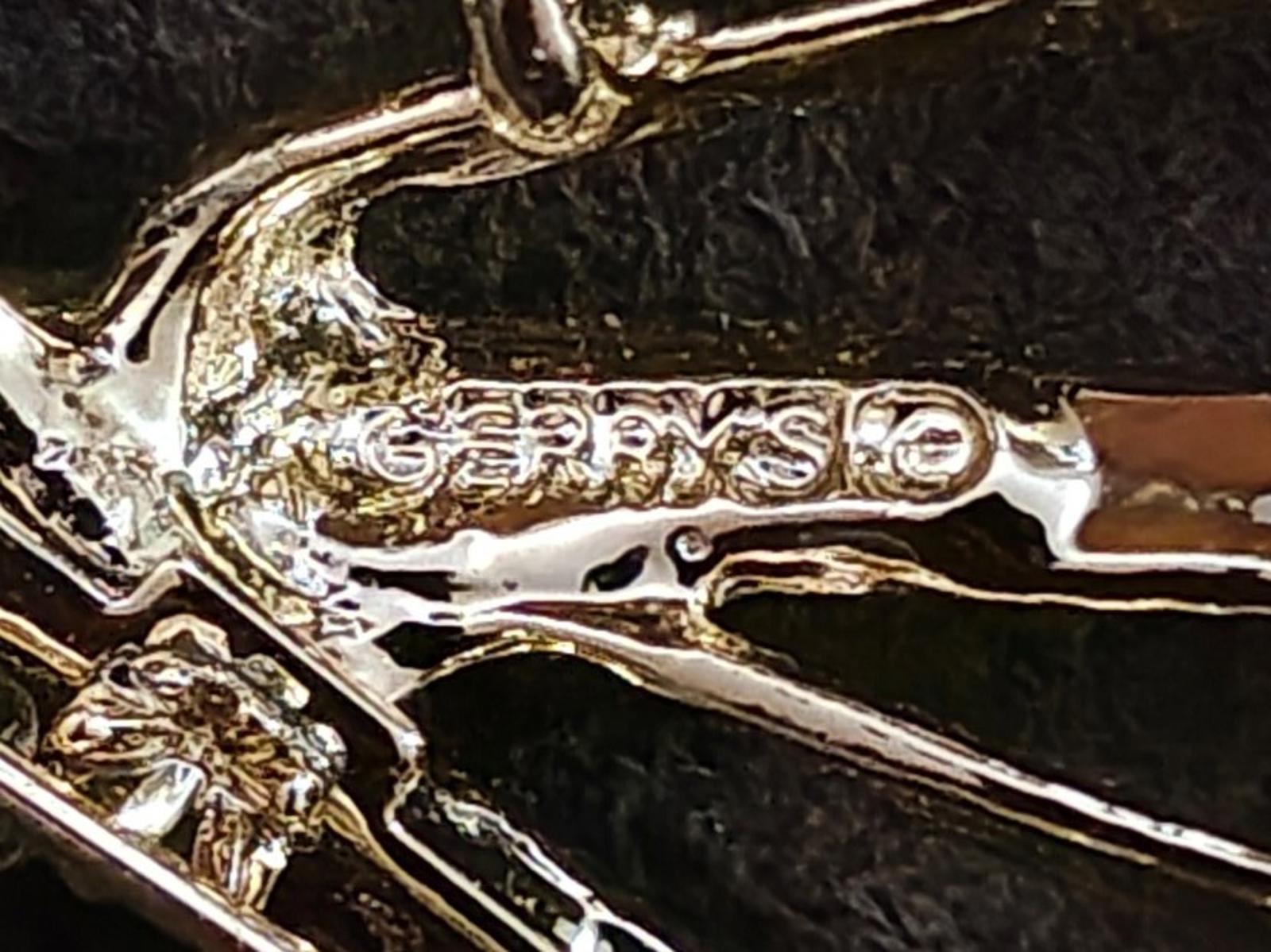 Close-up of gold-tone textured brooch pin metal with engraved pattern details