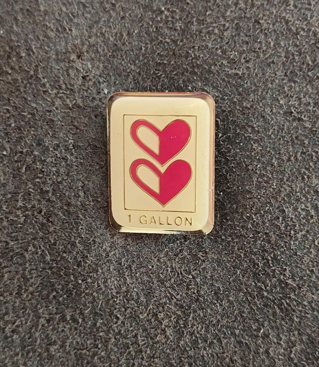 Gold-tone enamel pin with two red hearts and '1 GALLON' marking