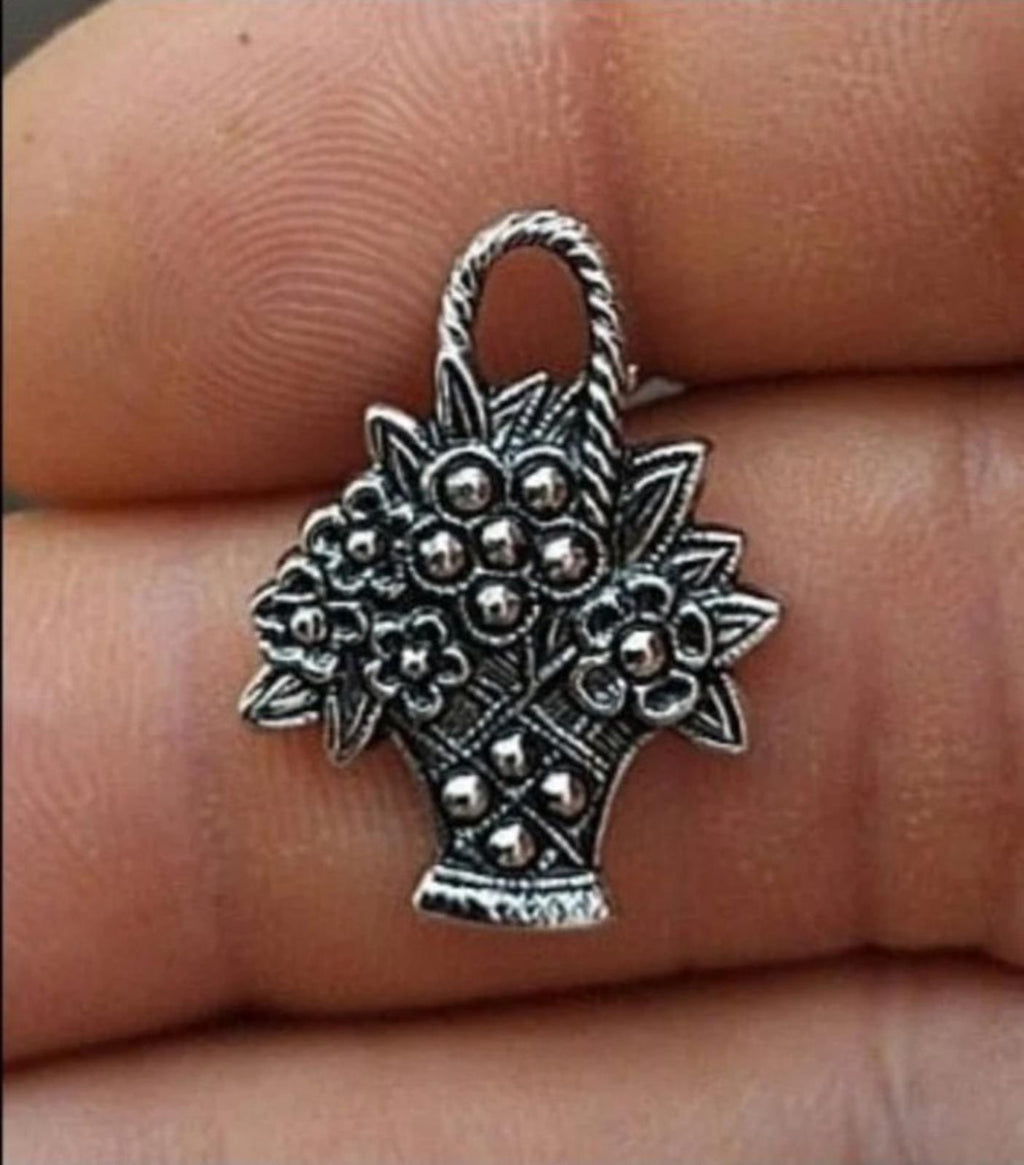 Antiqued silver-tone flower basket pin close-up on fingertip with raised floral details