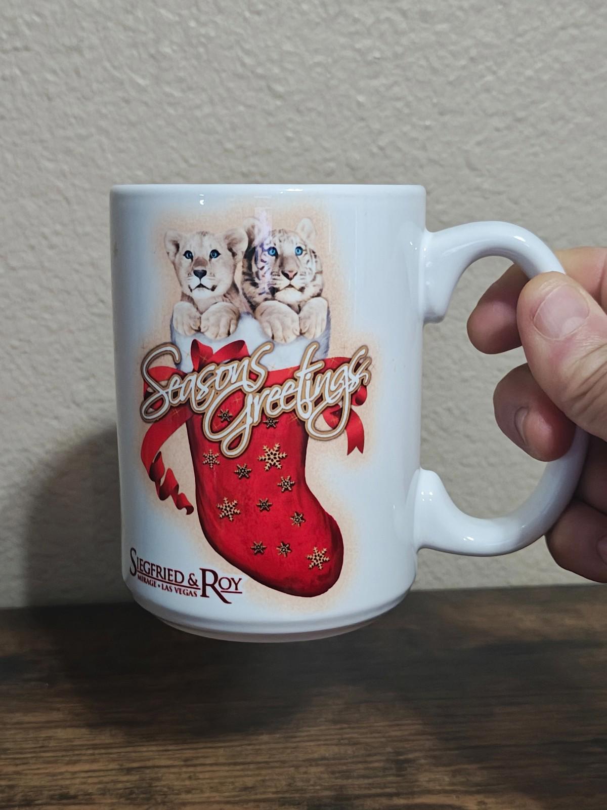 White porcelain mug with two big cats cuddling above a red “Seasons Greetings” stocking graphic