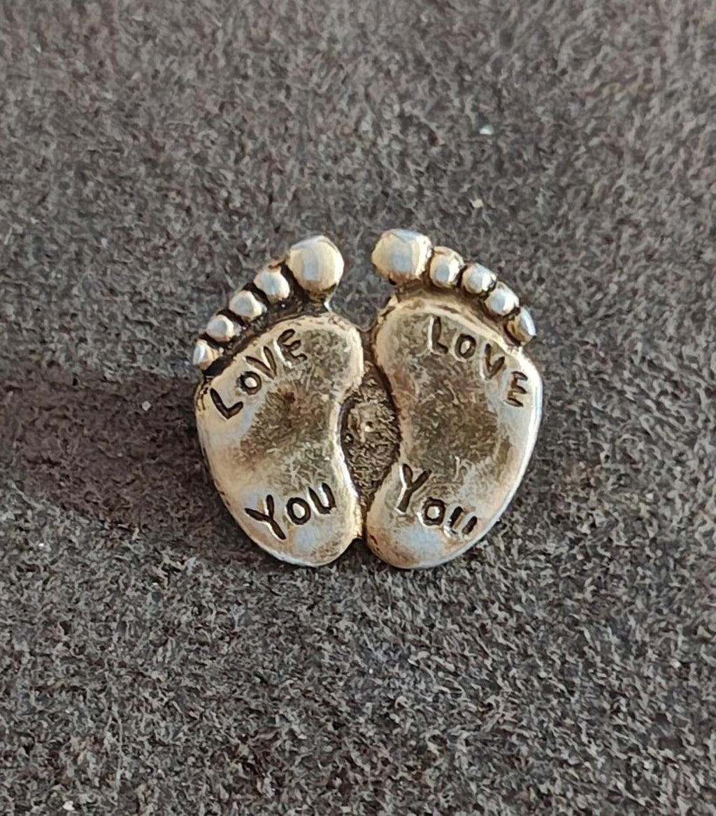 Gold-tone two-footprint brooch pin close-up with beaded rim and "LOVE YOU" text