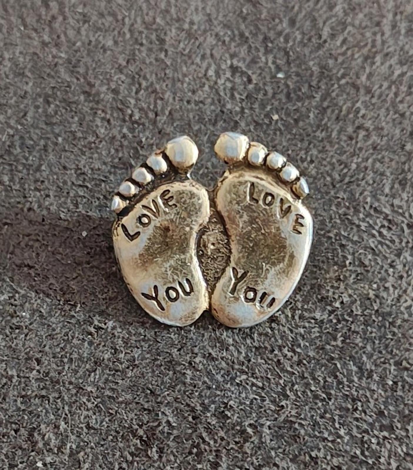 Gold-tone two-footprint brooch pin close-up with beaded rim and "LOVE YOU" text