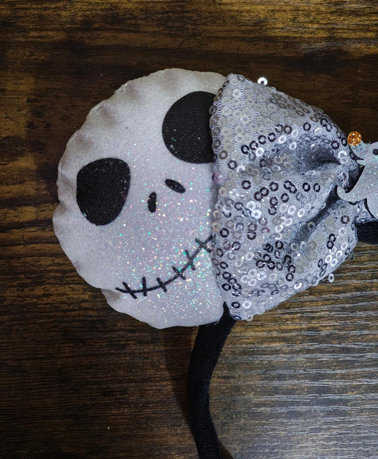 Round black-and-white skull ear with silver sequin bow on black headband