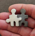 Puzzle-shaped brooch of two joined figures in white and dark gray ceramic look