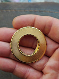 Gold-tone round scarf clip with textured rim and open oval clasp