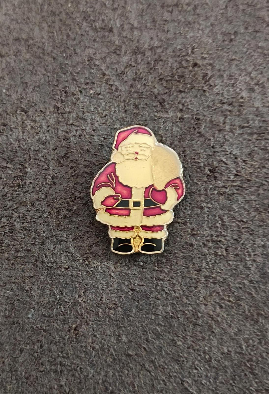Red Santa Claus enamel pin in gold-tone, holding a gift sack