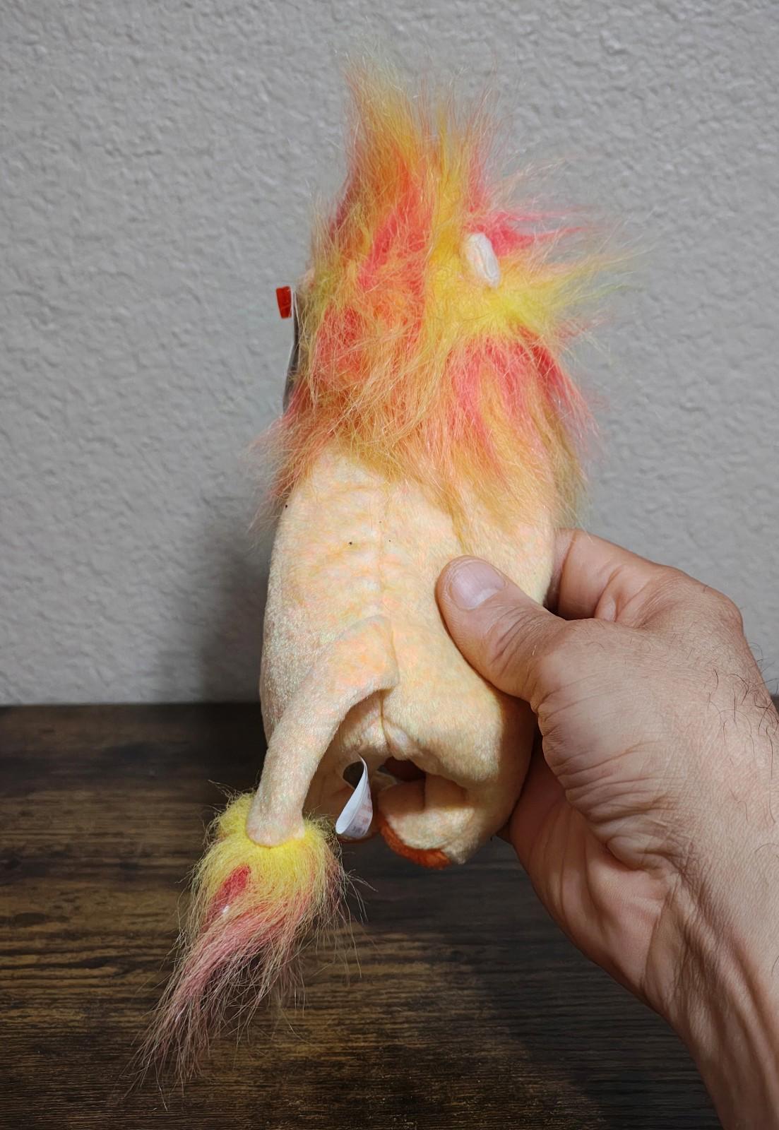 Rainbow-furred lion beanbag plush viewed from the side, hand holding body