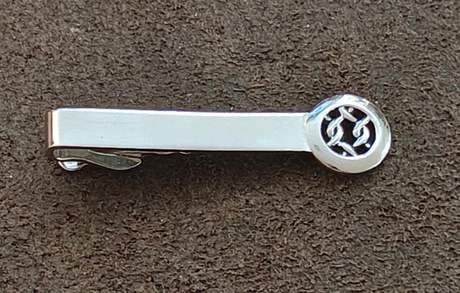 Silver tie bar clip showing round Celtic knot medallion and bar face