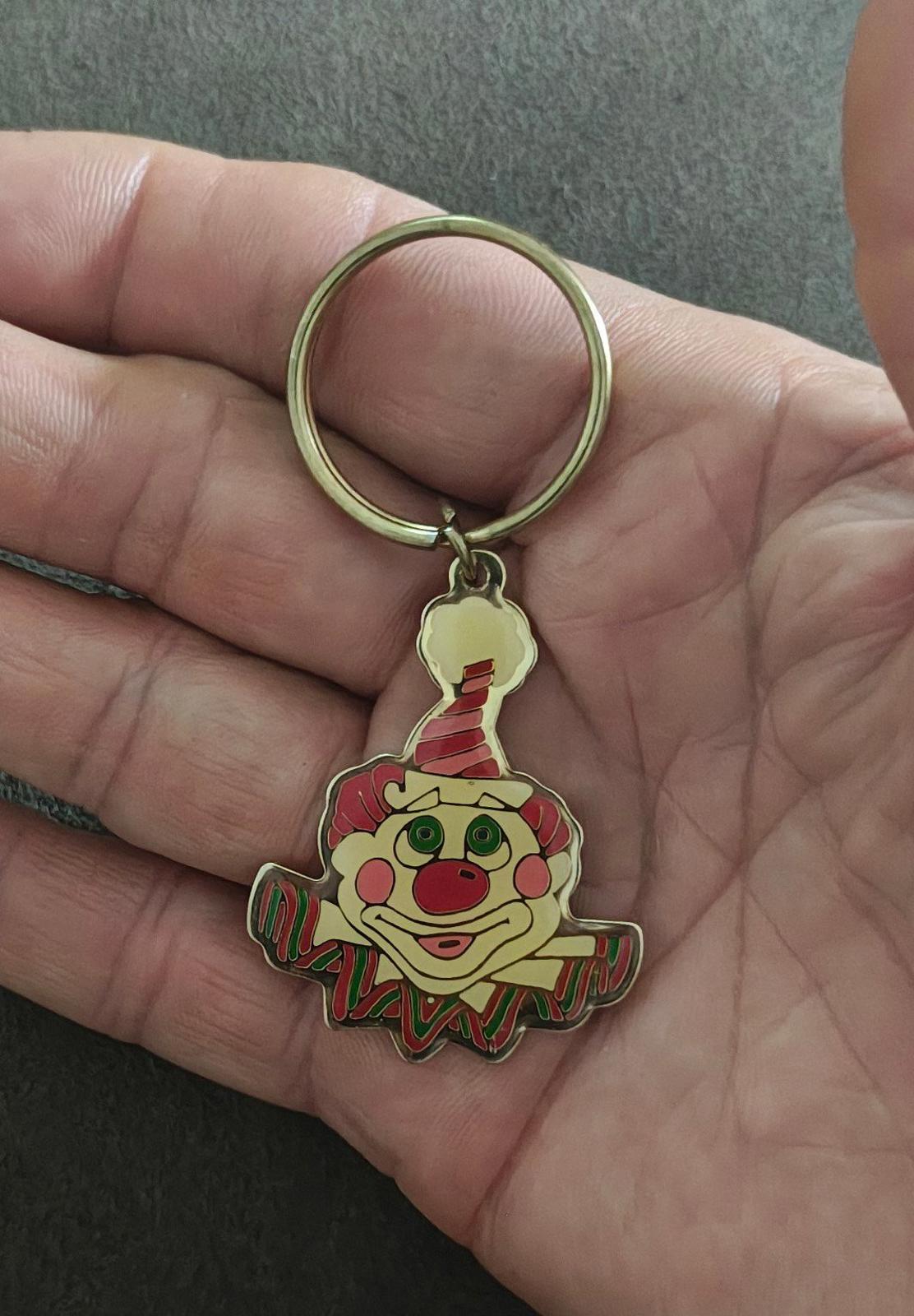 Gold-tone ring keychain with colorful clown face charm, close-up in hand